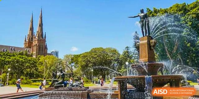 A scenic outdoor view of a park-like campus area with a fountain and trees at Wuxi Guanghua School.
