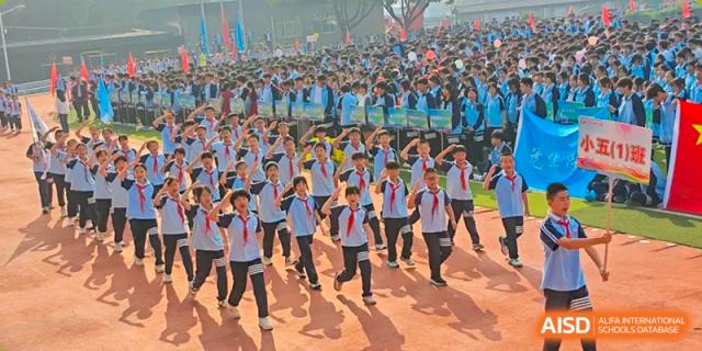 A large group of students marching in school uniforms during a school sports event or parade at Wuxi Guanghua School.