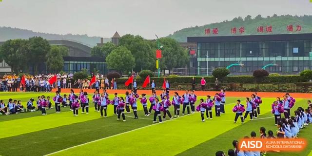 A large group of students in uniforms performing a synchronized routine on a sports field at Wuxi Guanghua School.