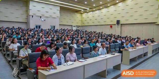 Teachers or parents attending a large lecture or meeting in an auditorium at Wuxi Guanghua School.