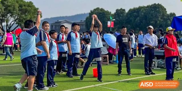 Students participating in an outdoor sports competition or team-building activity on the field at Wuxi Guanghua School.