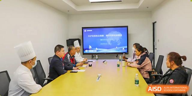 A group of students and a teacher from Beijing Lize International Academy have a discussion in a room with a large screen.