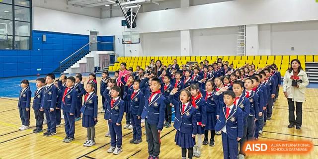 A large group of students from Beijing Lize International Academy stands in formation on a stage.