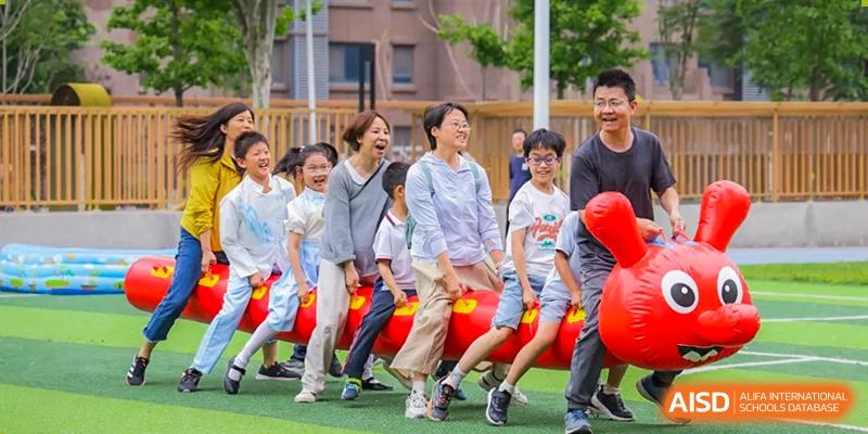 Students from Beijing Lize International Academy posing for a group photo in front of a red sculpture on a field.