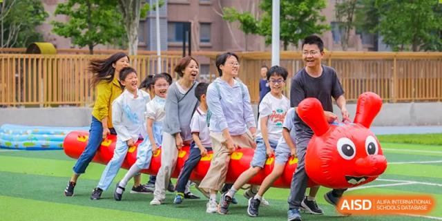 Students from Beijing Lize International Academy posing for a group photo in front of a red sculpture on a field.