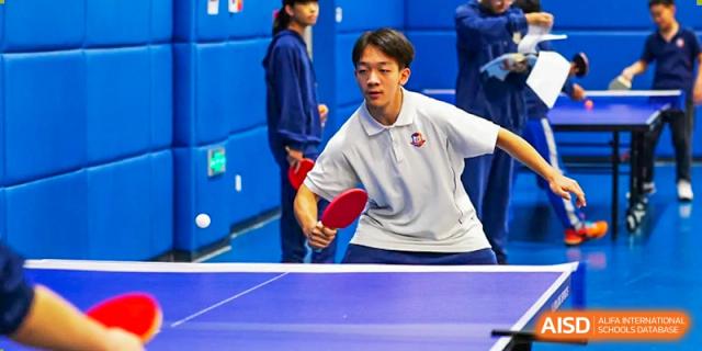 A student from Beijing Lize International Academy plays table tennis indoors.