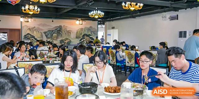 Students and teachers from Beijing Lize International Academy enjoy a meal together at a restaurant.