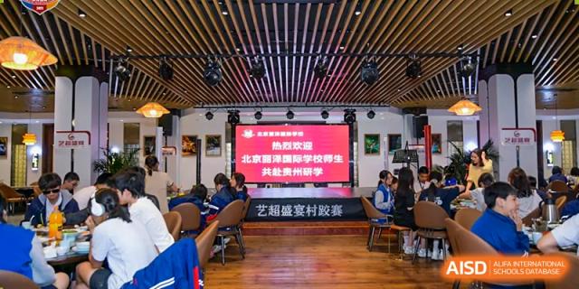 A large group of students and teachers from Beijing Lize International Academy sits in a formal meeting room.