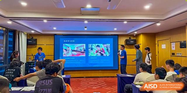 A classroom with students watching a presentation on a large screen at Beijing Mingcheng Academy.