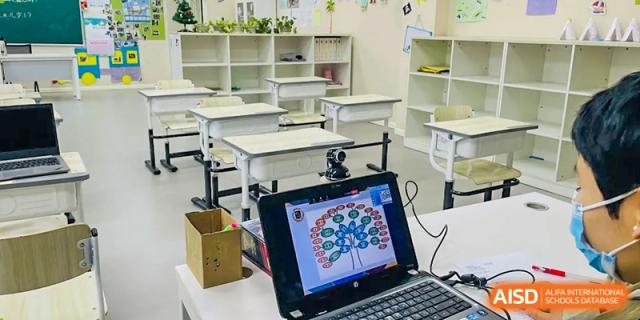 An empty, clean classroom with desks and a laptop on a table at Beijing Mingcheng Academy.