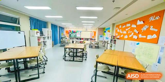 A brightly lit, empty classroom with colorful walls and desks at Beijing Mingcheng Academy.