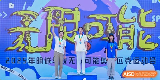 Students receiving medals and awards on a podium at Beijing Mingcheng Academy.