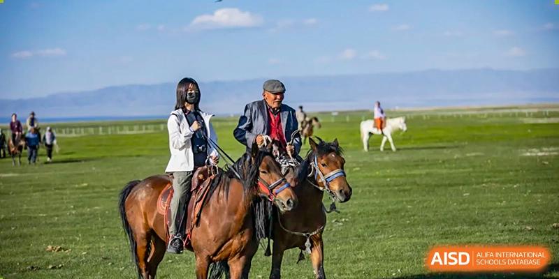 Students on horses in a grassy field at Beijing Mingcheng Academy.