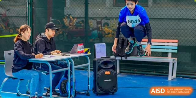 A student putting on a backpack next to a table with a speaker at Beijing Mingcheng Academy.