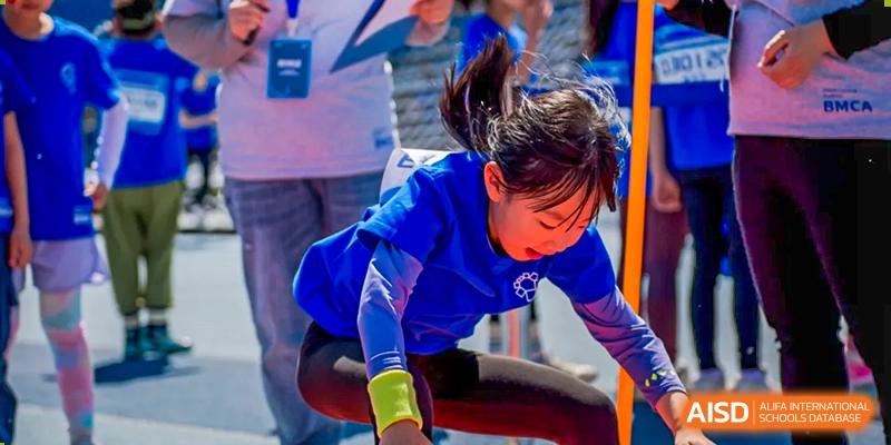A student in blue stretching or exercising on a track at Beijing Mingcheng Academy.