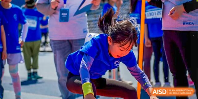 A student in blue stretching or exercising on a track at Beijing Mingcheng Academy.