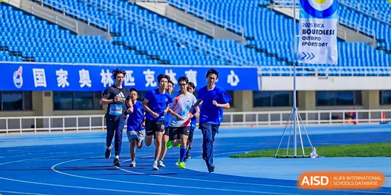 A group of students running a race on a blue track at Beijing Mingcheng Academy.