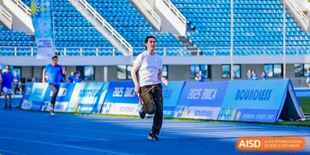 A man in a tracksuit jumping or performing a sports move on a track at Beijing Mingcheng Academy.