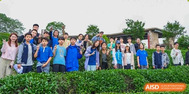 A group of students in blue tracksuits posing for a group photo outdoors at Beijing Mingcheng Academy.