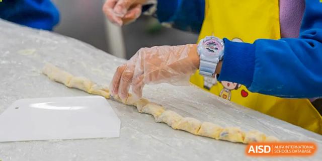 A close-up of hands rolling out dough for a cooking class at Beijing Mingcheng Academy.
