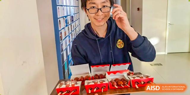 A student in glasses looking at pastries or baked goods at Beijing Mingcheng Academy.