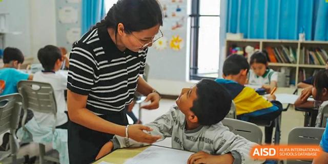 A teacher helps a young student from Kunming Concord College of Sino-Canada (CCSC) with a drawing in a classroom.