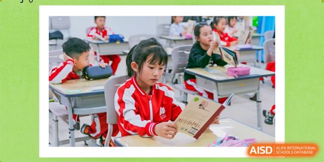 A young student from Kunming Concord College of Sino-Canada (CCSC) in a red and white uniform reads a book.