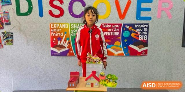 A young student from Kunming Concord College of Sino-Canada (CCSC) stands next to a stack of blocks in a classroom.