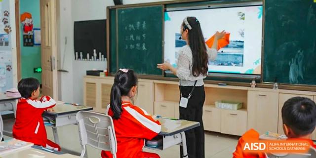 A teacher from Kunming Concord College of Sino-Canada (CCSC) stands at the blackboard, teaching a lesson to students.