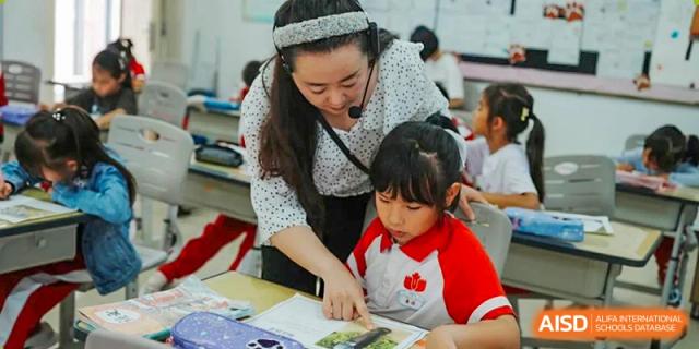 A teacher from Kunming Concord College of Sino-Canada (CCSC) helps a young student with their work in the classroom.