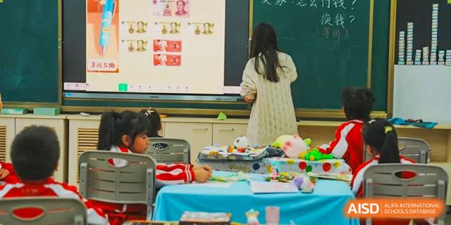 A student from Kunming Concord College of Sino-Canada (CCSC) works on a project at a table with other students.