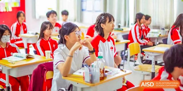 Students from Kunming Concord College of Sino-Canada (CCSC) are sitting at a table together, smiling and working on a project.