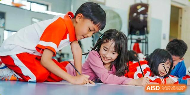 Two young students from Kunming Concord College of Sino-Canada (CCSC) are smiling as they work on a project together.