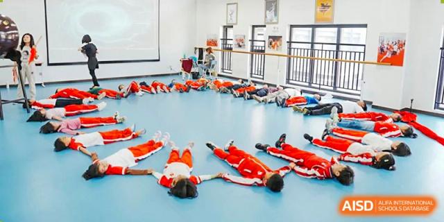 A group of students from Kunming Concord College of Sino-Canada (CCSC) are lying on the floor in a classroom during a training session.