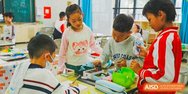 Two young students from Kunming Concord College of Sino-Canada (CCSC) are seated at a table and building something with blocks.