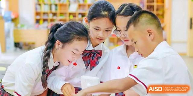Three female students from Kunming Concord College of Sino-Canada (CCSC) are looking at a book together and smiling.