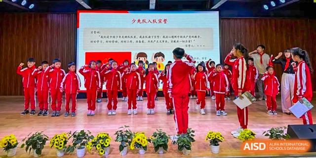 Students from Kunming Concord College of Sino-Canada (CCSC) perform a synchronized dance on a field while wearing red uniforms.