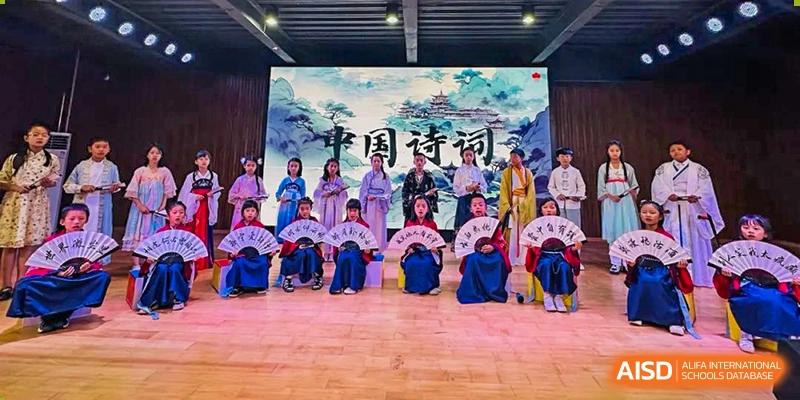 Students from Kunming Concord College of Sino-Canada (CCSC) perform a traditional dance on a stage decorated with a blue backdrop.