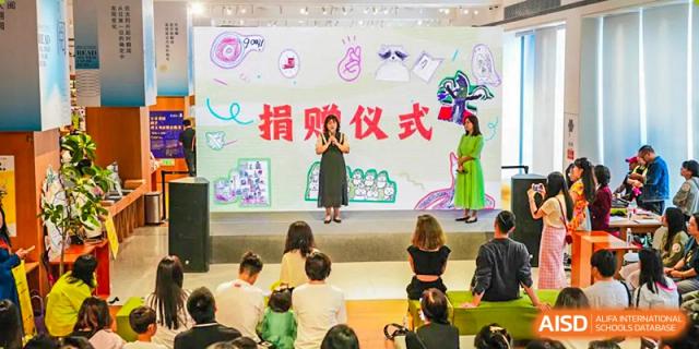 A female teacher from Kunming Concord College of Sino-Canada (CCSC) gives a speech or presentation to a seated audience.