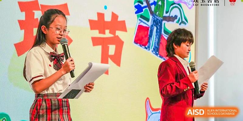 A close-up of a student's hand from Kunming Concord College of Sino-Canada (CCSC) holding a large red and white sign with Chinese characters.