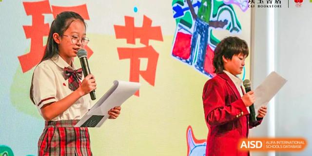 A close-up of a student's hand from Kunming Concord College of Sino-Canada (CCSC) holding a large red and white sign with Chinese characters.