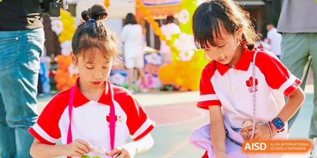 Two young students from Kunming Concord College of Sino-Canada (CCSC) wearing red jackets and smiling.