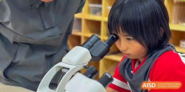 A student from Kunming Concord College of Sino-Canada (CCSC) looks through a microscope in a science class.