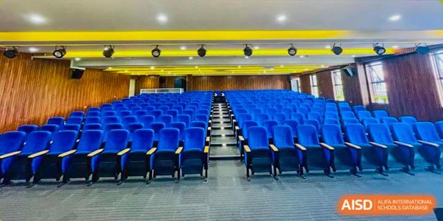 A photo of an empty auditorium with rows of blue seats at Kunming Concord College of Sino-Canada (CCSC).