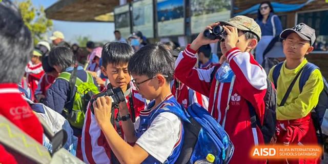 Two students from Kunming Concord College of Sino-Canada (CCSC) smile at the camera, with one wearing a backpack.