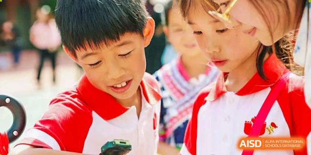 A young male student from Kunming Concord College of Sino-Canada (CCSC) smiles while another student is seen in the background.