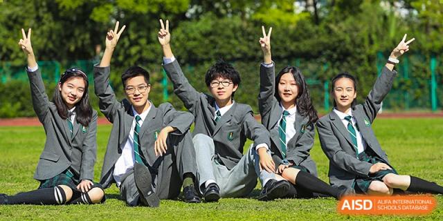 A group of happy students from Shanghai International High School of BANZ sitting on a grassy hill.