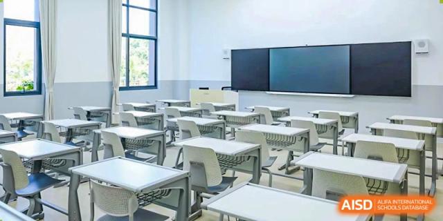 An empty classroom at Shanghai International High School of BANZ with rows of desks and chairs and large screen displays at the front.