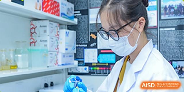 A student at Shanghai International High School of BANZ works in a laboratory, conducting an experiment with a pipette.