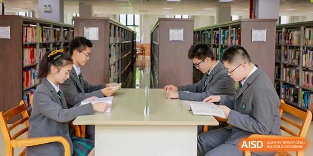 Students at Shanghai International High School of BANZ work together in a classroom, with one writing notes and the other looking at a tablet.